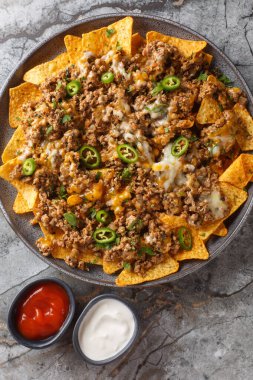 Baharatlı sığır kıymalı peynirli cips ve masada erimiş peynirle kaplı peynirli cips. Yukarıdan dikey üst görünüm