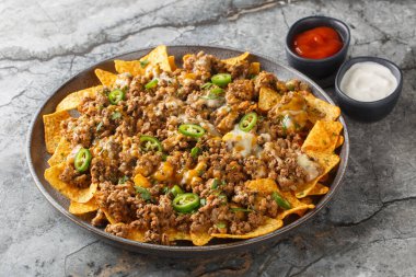 Biberli kıymalı ve peynirli cips, biberli, bitkisel ve soslu, masanın üzerindeki tabağa yakın. Yatay