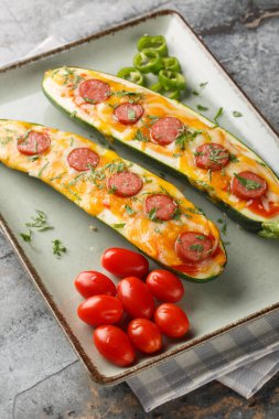 Çedar peyniri, mozzarella peyniri, sosis ve domates sosuyla pişirilmiş düşük karbonhidratlı pizza tekneleri masanın üstünde. Dikey