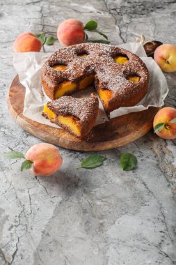 Masadaki tahtaya yakın plan şeftali ile doldurulmuş çikolatalı meyveli kek. Dikey