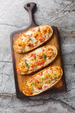 Masanın üzerinde peynirli karides sarımsaklı ekmek, mozzarella, domates ve maydanozun yakın çekimi var. Yukarıdan dikey üst görünüm