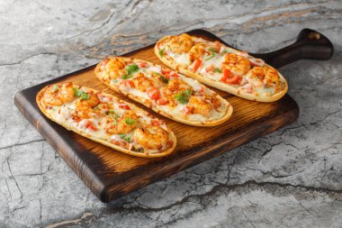 Masanın üzerinde karides, peynir, sarımsak ve domatesli leziz sıcak sandviçler. Yatay