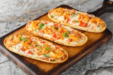 Masanın üzerinde karides, peynir, sarımsak ve domatesli açık panini sandviçleri. Yatay