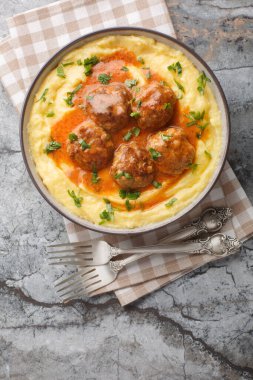 Baharatlı soslu köfte ve yanında mısır lapası. Masadaki kaseye yakın. Yukarıdan dikey üst görünüm