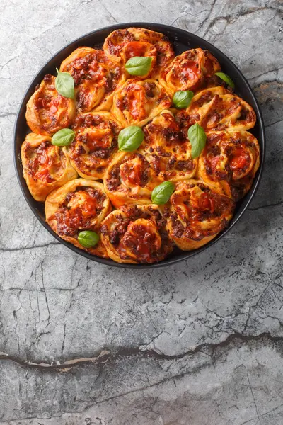 stock image Hot pizza roll with tomatoes, cheese, Italian sausages and basil close-up in baking dish on table. Vertical top view from abov