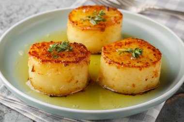 Tereyağı, eritilmiş patates, sarımsak, taze otlar ve taze otlarla pişirilmiş. Masanın üzerindeki tabakta bir kaşık dolusu kremalı tat oluşturuyor. Yatay