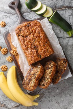 Masadaki tahtanın üzerinde ev yapımı muzlu kabaklı ekmek cevizli ve çikolatalı kapak resmi. Yukarıdan dikey üst görünüm