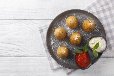 Typical Sicilian dish arancini served with two sauces close-up in a plate on a wooden table. Horizontal top view from abov clipart