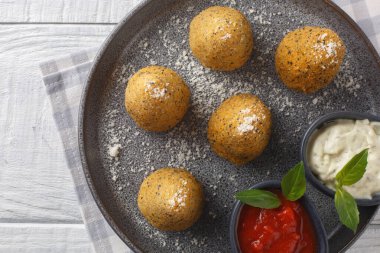 Peynirle doldurulmuş ev yapımı risotto Arancini. Ahşap bir masada iki sosla servis ediliyor. Yukarıdan yatay üst görünüm