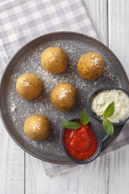 Arancini, ahşap bir masada yakın plan bir tabakta iki sosla servis edilen peynir ve biberle doldurulmuş İtalyan pirinç toplarıdır. Yukarıdan dikey üst görünüm