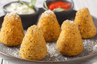 Peynirle doldurulmuş ev yapımı risotto Arancini. Ahşap bir masada iki sosla servis ediliyor. Yatay