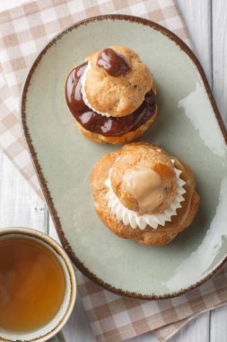 Din profiterolleri, biri diğerinden daha büyük iki choux pastadan yapılmış ve genellikle tabağın üzerinde kremalı pastalarla dolu bir Fransız hamur işidir. Yukarıdan dikey üst görünüm