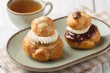 Dindar Choux çörekleri vanilyalı krema ve çikolatayla dolu ya da yakın plan kahve jöleli tahta bir masada. Yatay