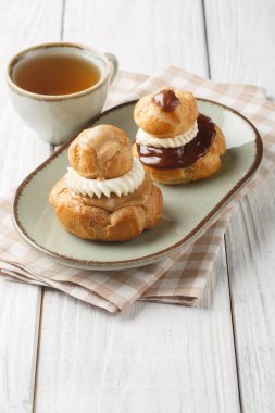 Din profiterolleri, biri diğerinden daha büyük olmak üzere iki choux pastasından yapılmış ve genellikle ahşap masanın üzerindeki pasta kremalı kapakla dolu bir Fransız hamur işidir. Dikey