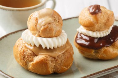 Dindar Fransız choux tatlısı muhallebi ile dolu ahşap masadaki tabağa yakın plan. Yatay