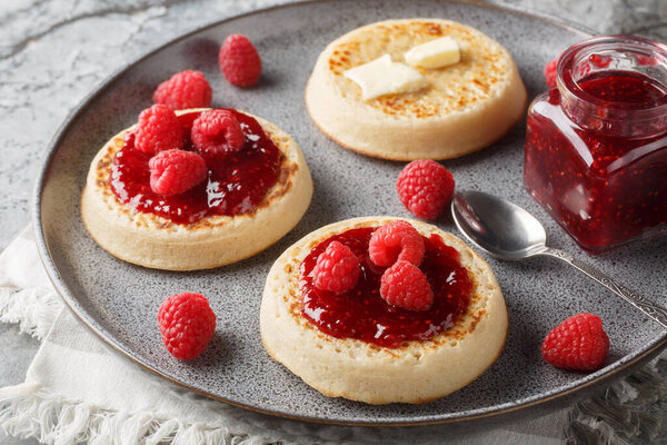 Свежеподжаренные булочки на блюдах с маслом, джемом и свежей малиной крупным планом на тарелке на столе. Фалонта