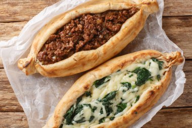 Pide Türk Düz Ekmek Pizzası, kıymalı, peynirli, ıspanaklı ve otlu ahşap tahtaya yakın plan. Yukarıdan yatay üst görünüm