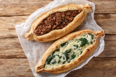 Geleneksel Türk usulü fırında pişirilmiş pide, ahşap tahtada kıyma, peynir, ıspanak ve baharatlı yakın plan. Yukarıdan yatay üst görünüm