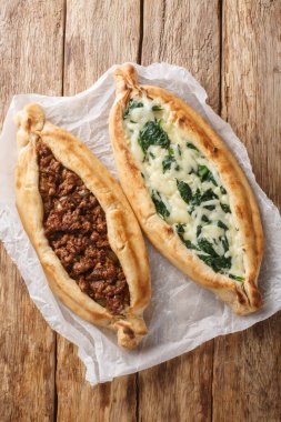 Tahta masaya yakın ıspanaklı kıyma ve peynirli Türk Pide pizzası. Yukarıdan dikey üst görünüm