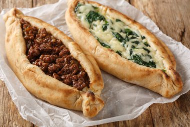 Geleneksel Türk usulü fırında pişirilmiş pide, ahşap tahtada kıyma, peynir, ıspanak ve baharatlı yakın plan. Yatay