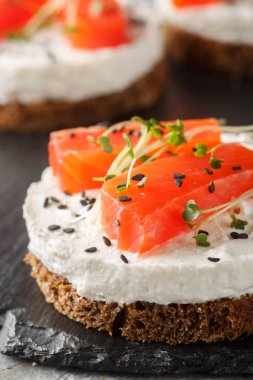 Tuzlu peynirli kek, açık sandviç, somonlu tost, krem peynir, susam ve mikro yeşillikler masaya yakın plan sağlıklı kahvaltı için. Dikey