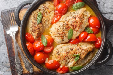 Homemade spicy chicken fillet stewed with onions, garlic and tomatoes close-up in a frying pan on the table. Horizontal top view from abov clipart