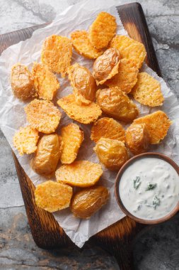 Parmesan kabuklu bebek yeni patatesler. Ekşi krema sosuyla servis ediliyor. Masanın üzerindeki tahta tahtaya yakın. Yukarıdan dikey üst görünüm