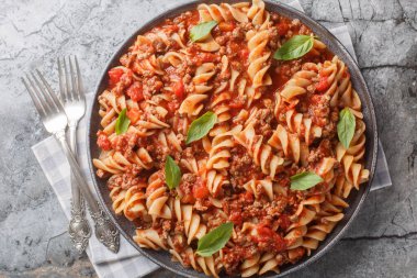 Etli bolonez soslu baharatlı fusilli makarna masanın üstünde. Yukarıdan yatay üst görünüm