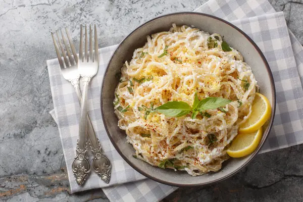 Limon peyniri soslu spagetti makarna, ricotta, parmesan peyniri ve fesleğen yakın plan, masanın üstünde. Yukarıdan yatay üst görünüm