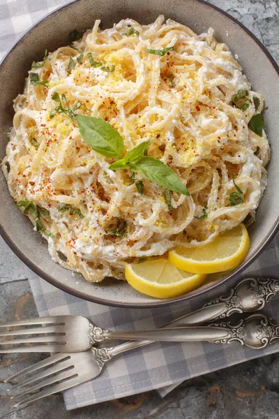 Ricotta peynirli kremalı spagetti, limon aromalı ve meyve suyu, parmesan, biber ve fesleğeni masaya yakın bir kasede. Yukarıdan dikey üst görünüm