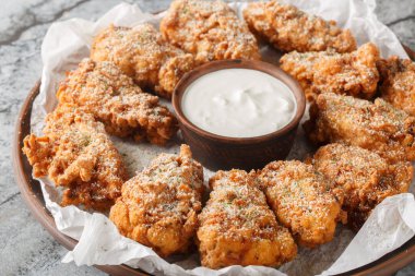 Breaded Bburinkle fried chicken wings in cheese garlic onion breading with dipping sauce close-up in plate on table. Horizonta clipart