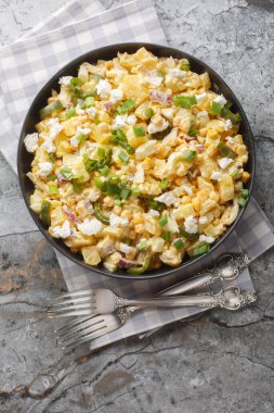 Mexican Street Corn Potato Salad with spicy jalapenos, boiled eggs, fresh green and red onions, and salty cotija cheese closeup on the plate on the table. Vertical top view from abov clipart