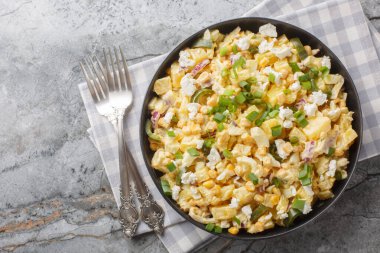 Lezzetli Meksika usulü Patates Salatası, yanında da salamura jalapeno, haşlanmış yumurta, soğan ve masaya yakın tabakta cotija peyniri. Yukarıdan yatay üst görünüm