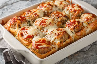 Köftelerle doldurulmuş fırında rulo köfte, üstüne domates sosu ve masaya yakın plan peynir serpiştirilmiş. yatay