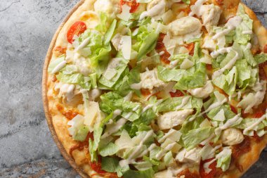 Tavuklu, marullu, domatesli, peynirli ve krem soslu beyaz Sezar pizzası. Masanın üzerindeki ahşap tahtaya yakın plan. Yukarıdan yatay üst görünüm