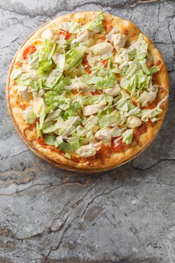 Tavuklu, parmesanlı, vişneli domatesli ve masadaki tahtaya yakın taze marullu pizza Sezar salatası. Yukarıdan dikey üst görünüm