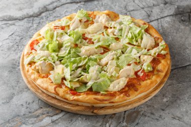 Narin soslu, peynirli, domatesli, tavuklu ve marullu Sezar pizzası masanın üstünde. yatay