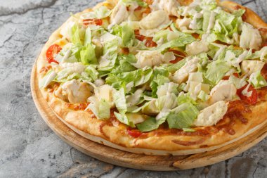 Tavuklu, marullu, domatesli, peynirli ve krem soslu beyaz Sezar pizzası. Masanın üzerindeki ahşap tahtaya yakın plan. Yatay