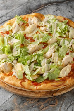 Tavuklu, parmesanlı, vişneli domatesli ve masadaki tahtaya yakın taze marullu pizza Sezar salatası. Dikey