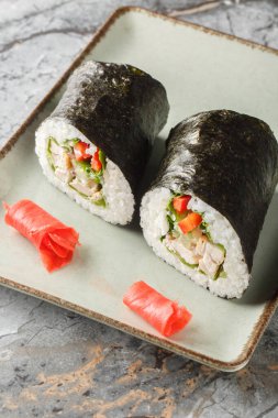 Fresh sushi burrito with rice, chicken, cream cheese, vegetables and lettuce wrapped in nori seaweed close-up in a plate on the table. Vertica clipart