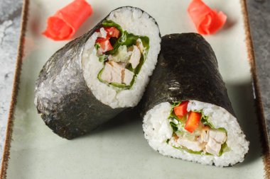 Sushirrito with rice, chicken breast, cream cheese, vegetables, nori and lettuce close-up in a plate on the table. horizonta clipart