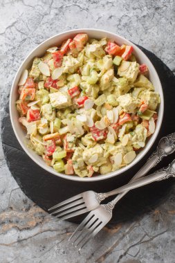 Masanın üzerinde kereviz, soğan, biber ve badem taneli ev yapımı Genovese Pesto Tavuk Salatası var. Yukarıdan dikey üst görünüm