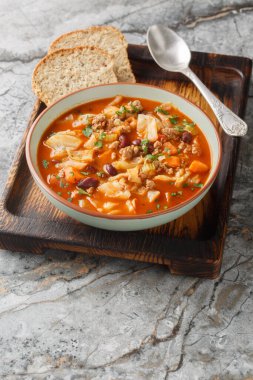 Sığır eti ve lahana çorbası, baharatlı sığır eti, lahana, havuç, kereviz, fasulye ve masaya yakın duran doğranmış domateslerle doludur. Dikey