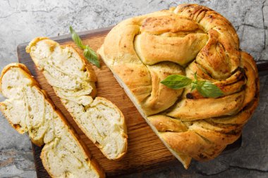 Masanın üzerindeki ahşap tahtada soslu pesto ekmeği yakın plan örülmüş. Yukarıdan yatay üst görünüm