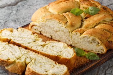 Masanın üzerindeki ahşap tahtada soslu pesto ekmeği yakın plan örülmüş. Yatay