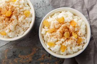 Tarçınlı tatlı pirinç pudingi ve masanın üstündeki ramekin 'in üstünde üzümler. Yukarıdan yatay üst görünüm