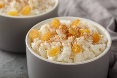 Tarçınlı tatlı pirinç pudingi ve masanın üstündeki ramekin 'in üstünde üzümler. Yatay