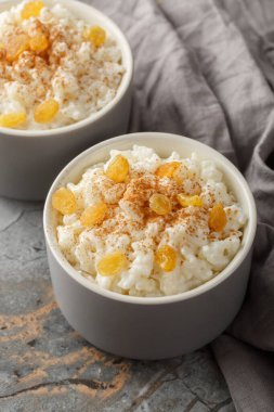 Tarçınlı, vanilyalı ve kuru üzümlü lezzetli sütlaç masanın üzerindeki kaseye yakın plan. Dikey