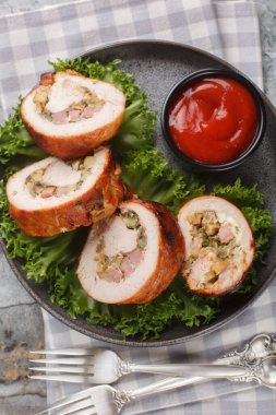 Domuz pastırması, soğan ve mantarla doldurulmuş hindi eti, masada yakın plan domates sosuyla servis edilir. Yukarıdan dikey üst görünüm