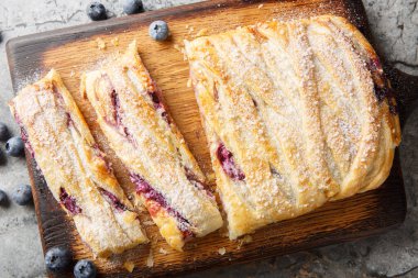 Taze yaban mersini ve krem peynirli poğaça masadaki tahtaya yakın çekim dolduruyor. Yukarıdan yatay üst görünüm